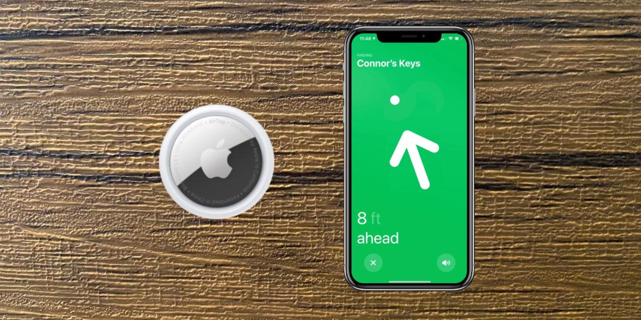An AirTag sat next to an iPhone using Find My against a wooden background