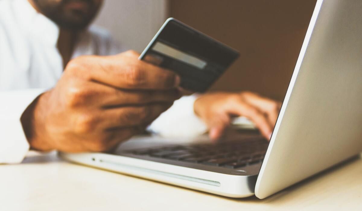 Man using credit card to purchase on MacBook