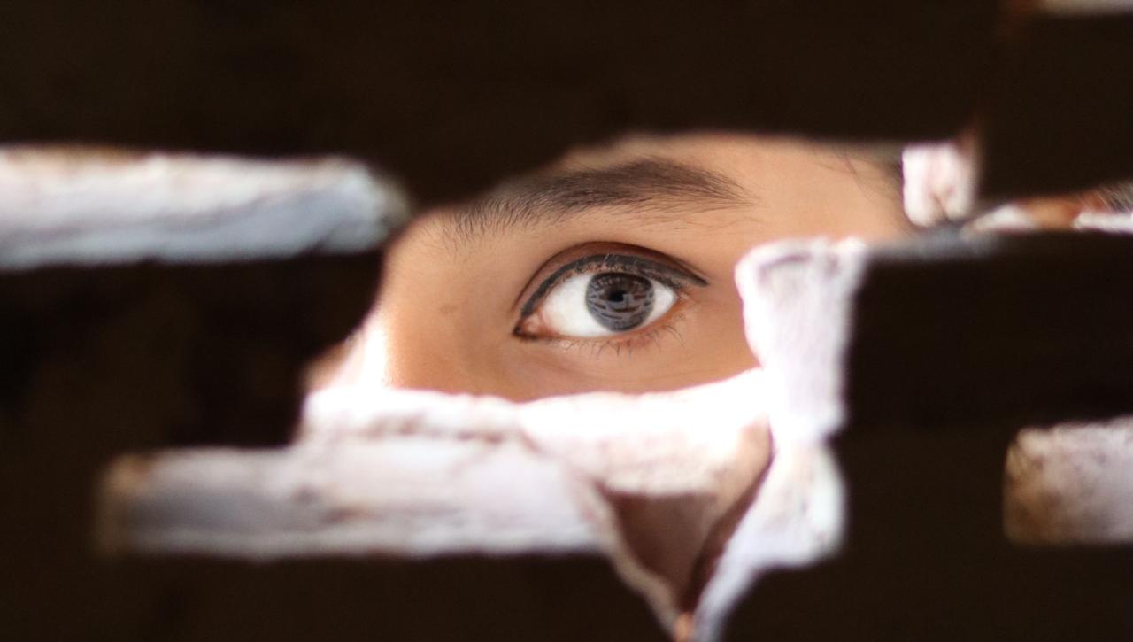 person looking through hole in brick wall